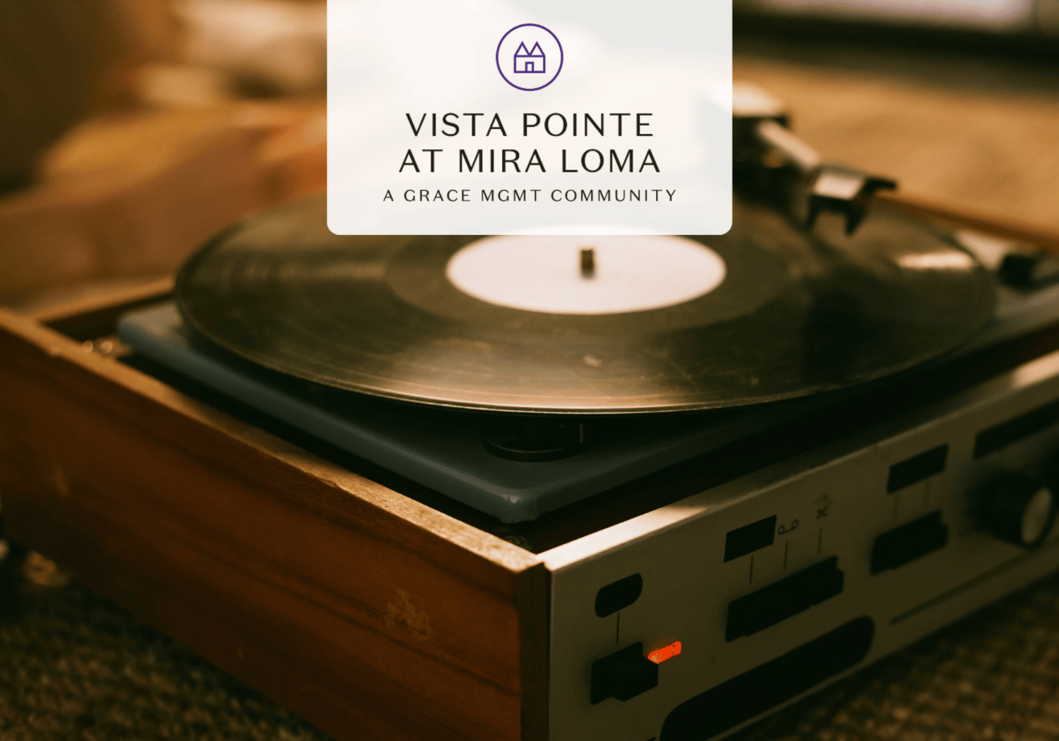 Turntable on a wooden cabinet with a white logo card reading 'Vista Pointe at Mira Loma, A Grace Mgmt Community' overlaying the scene.
